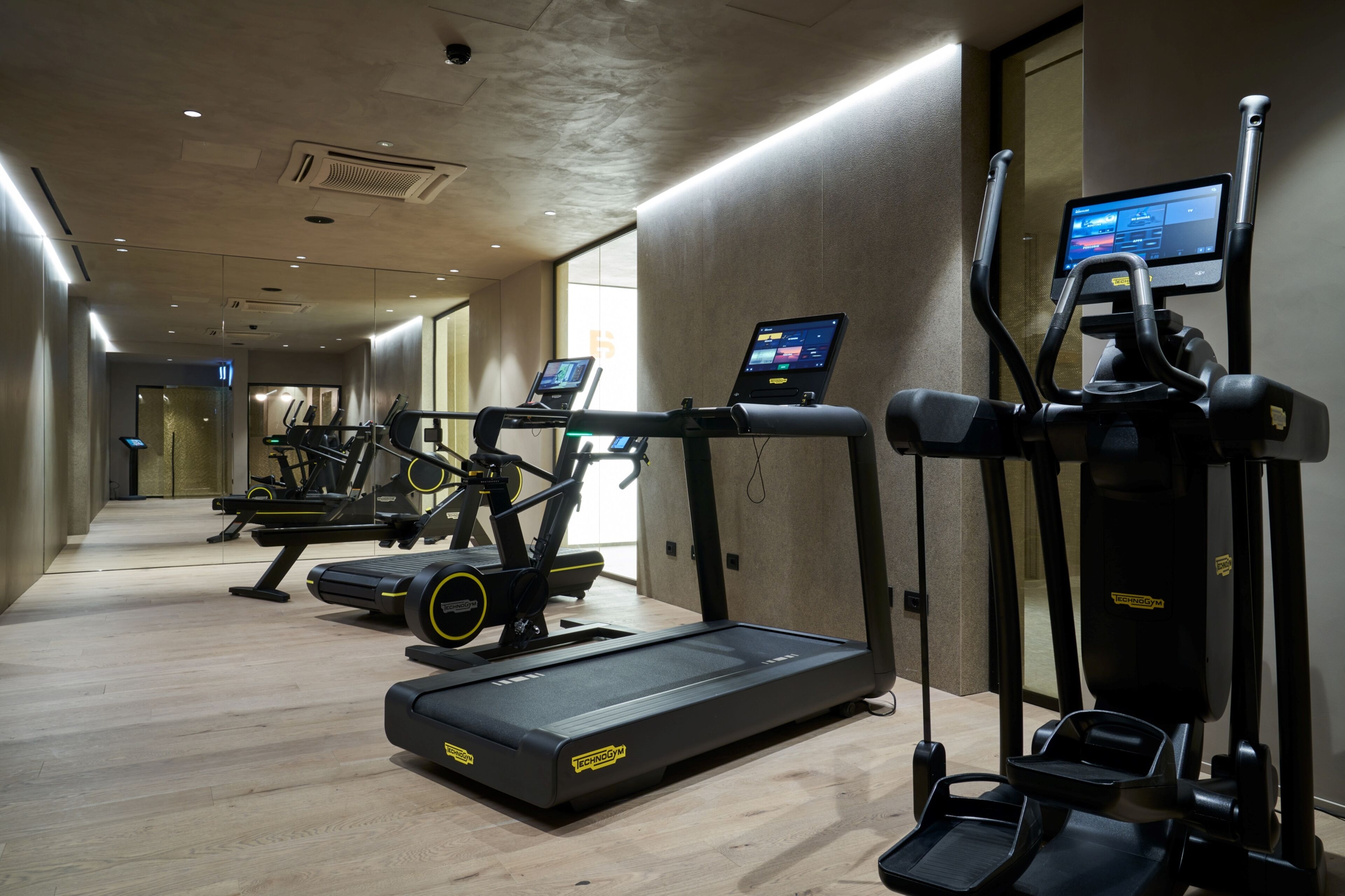 A modern gym with treadmills, elliptical machines, and a rowing machine.