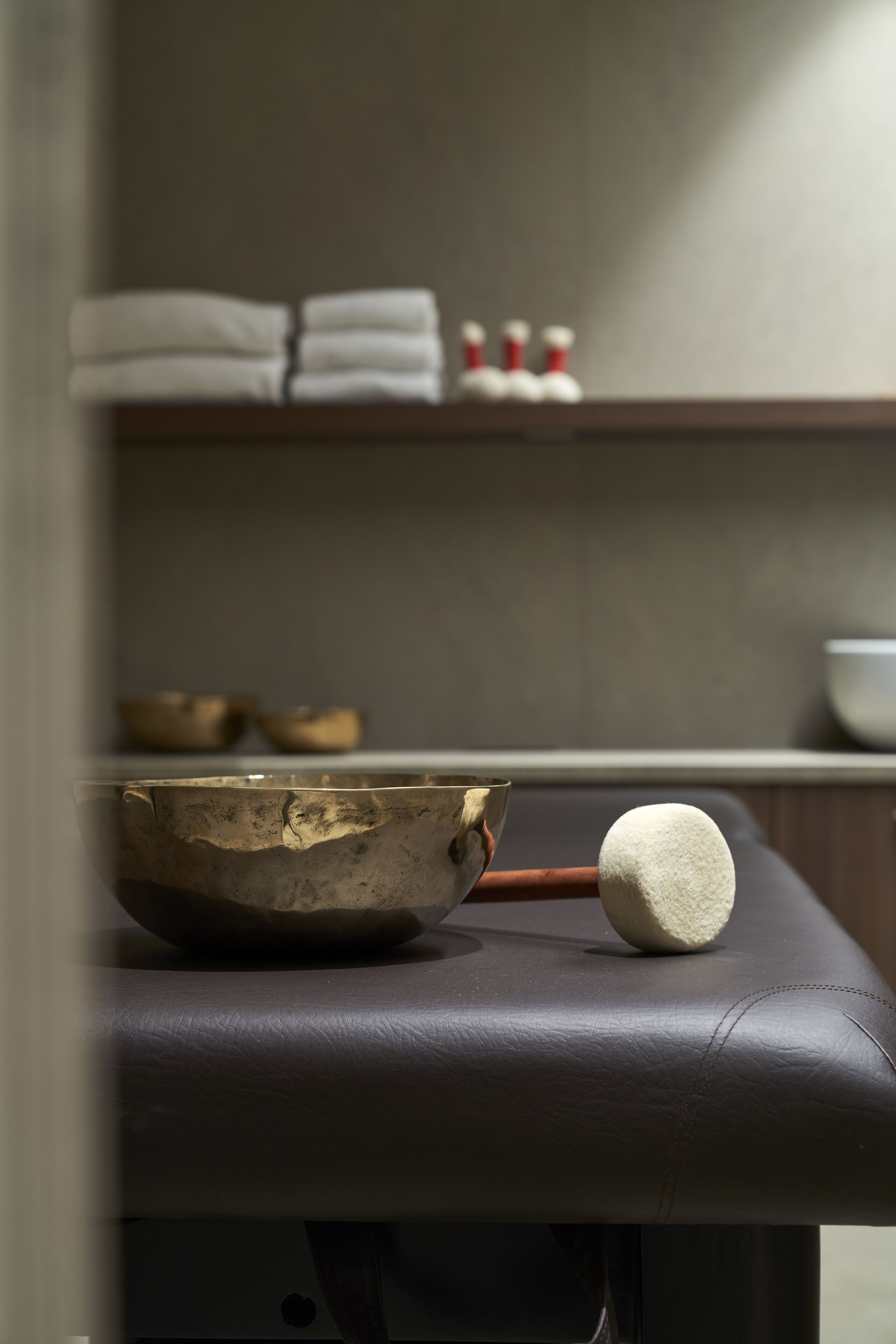Un espacio para meditar con un cuenco de meditación, un mazo y un estante con toallas dobladas y recipientes pequeños.