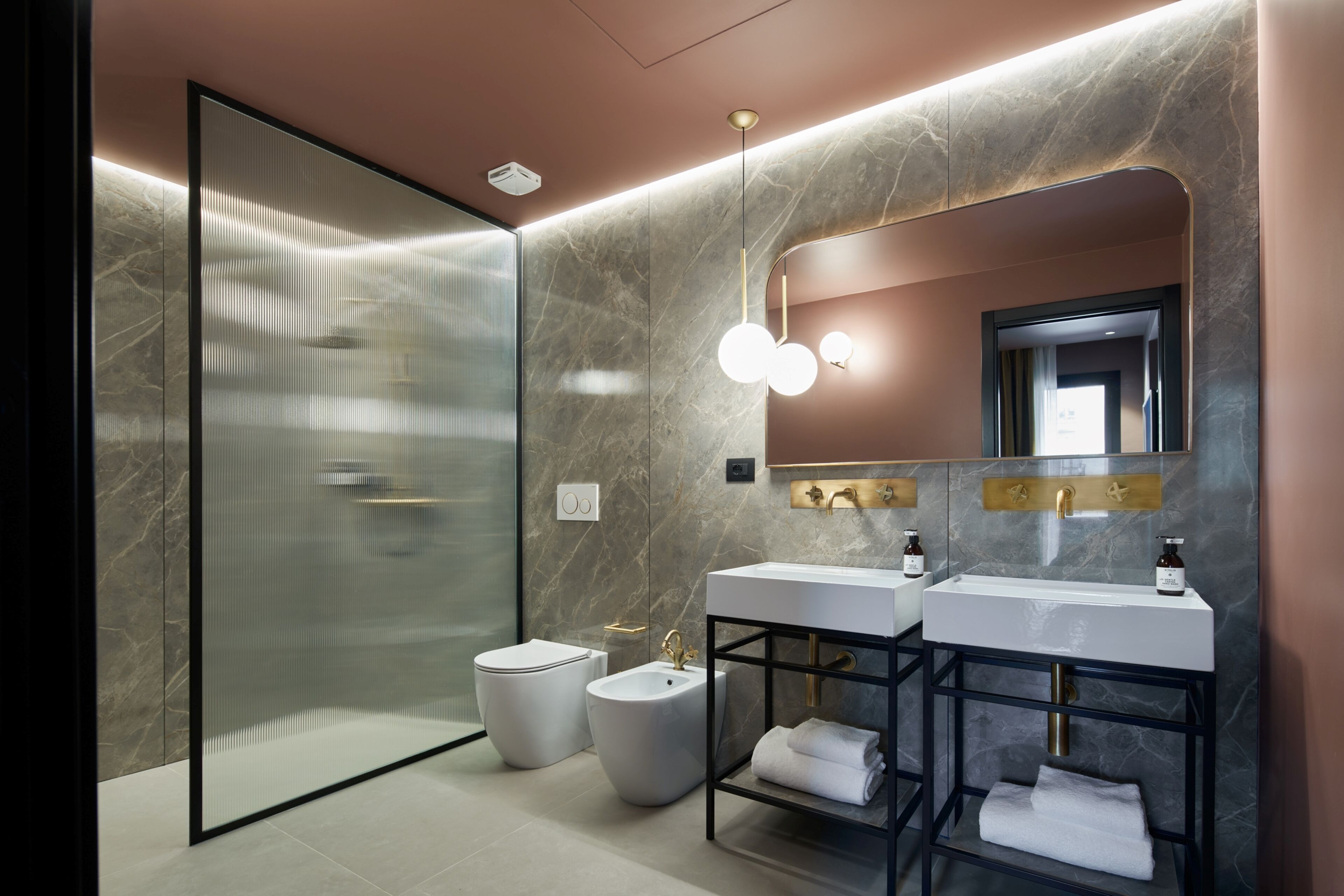 Un bagno moderno con cabina doccia in vetro, due lavabi e uno specchio grande.