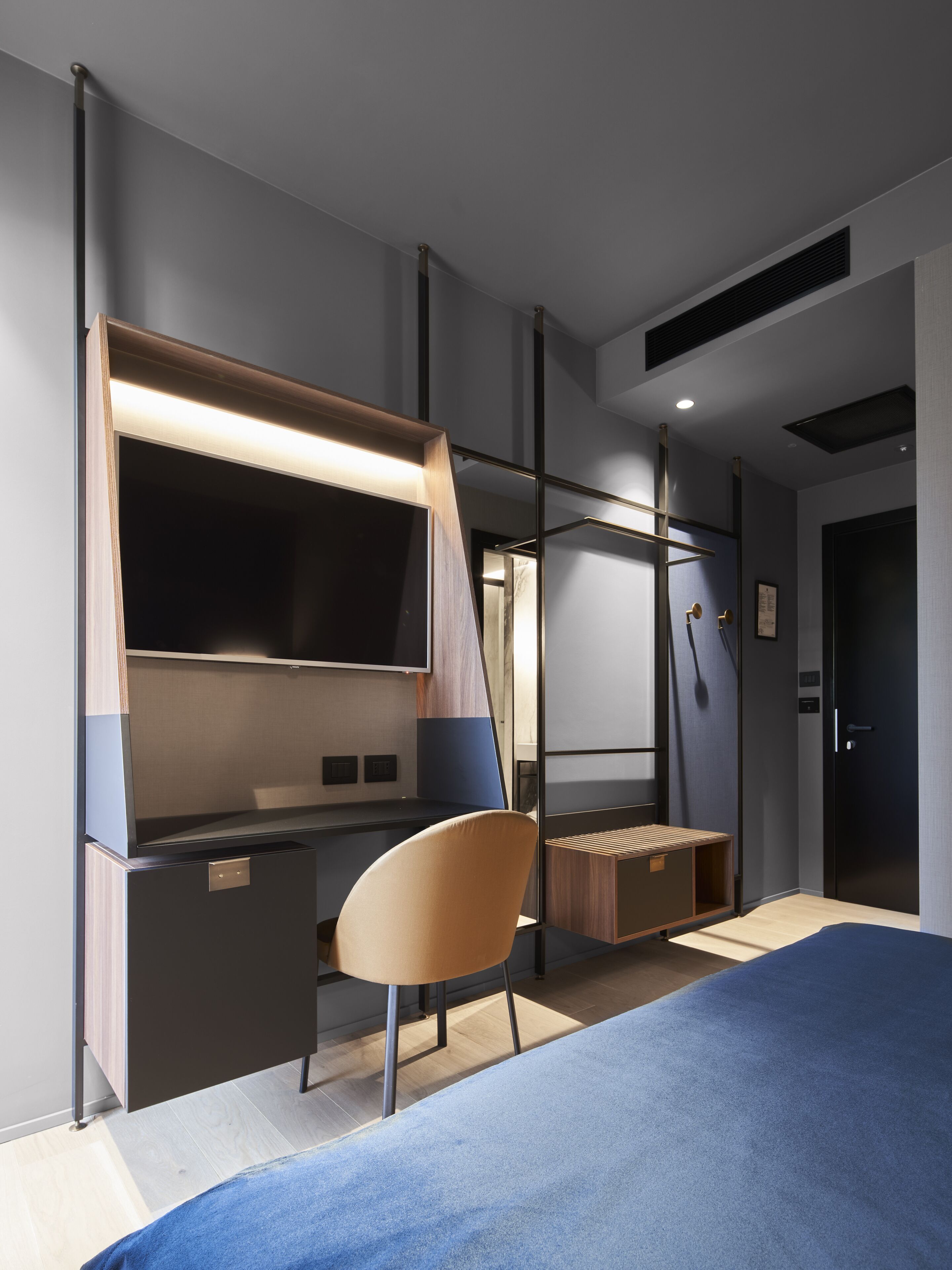 A modern bedroom with a bed, desk, chair, and a large mirror.