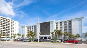 Situated on a vibrant street, this hotel features a striking facade with a large, textured wall and arched windows.