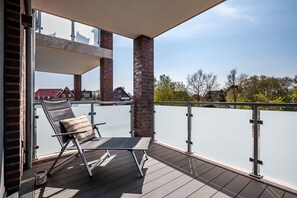 Enjoy the view from this balcony with a metal-framed chair and striped cushion, surrounded by brick pillars and a flat roof.