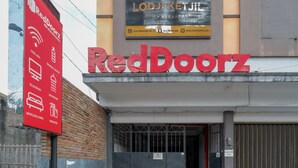 A RedDoorz hotel entrance with a signboard advertising amenities like free WiFi, mineral water, television, and a spotlessly clean linen. - Reddoorz Near Jogja Expo Center 2 (Banguntapan)