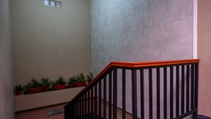 A staircase with black railings and a red handrail, leading to a landing with potted plants. - Reddoorz Near Jogja Expo Center 2 (Banguntapan)