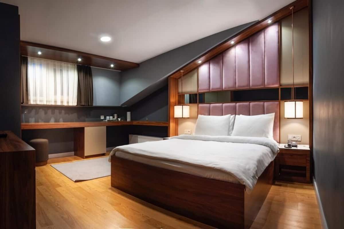 A modern bedroom with a large bed, a desk, and a built-in bench.