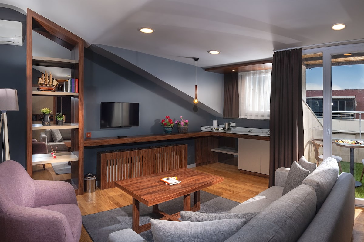 A modern living room with a sofa, a coffee table, a TV, and a bookshelf.