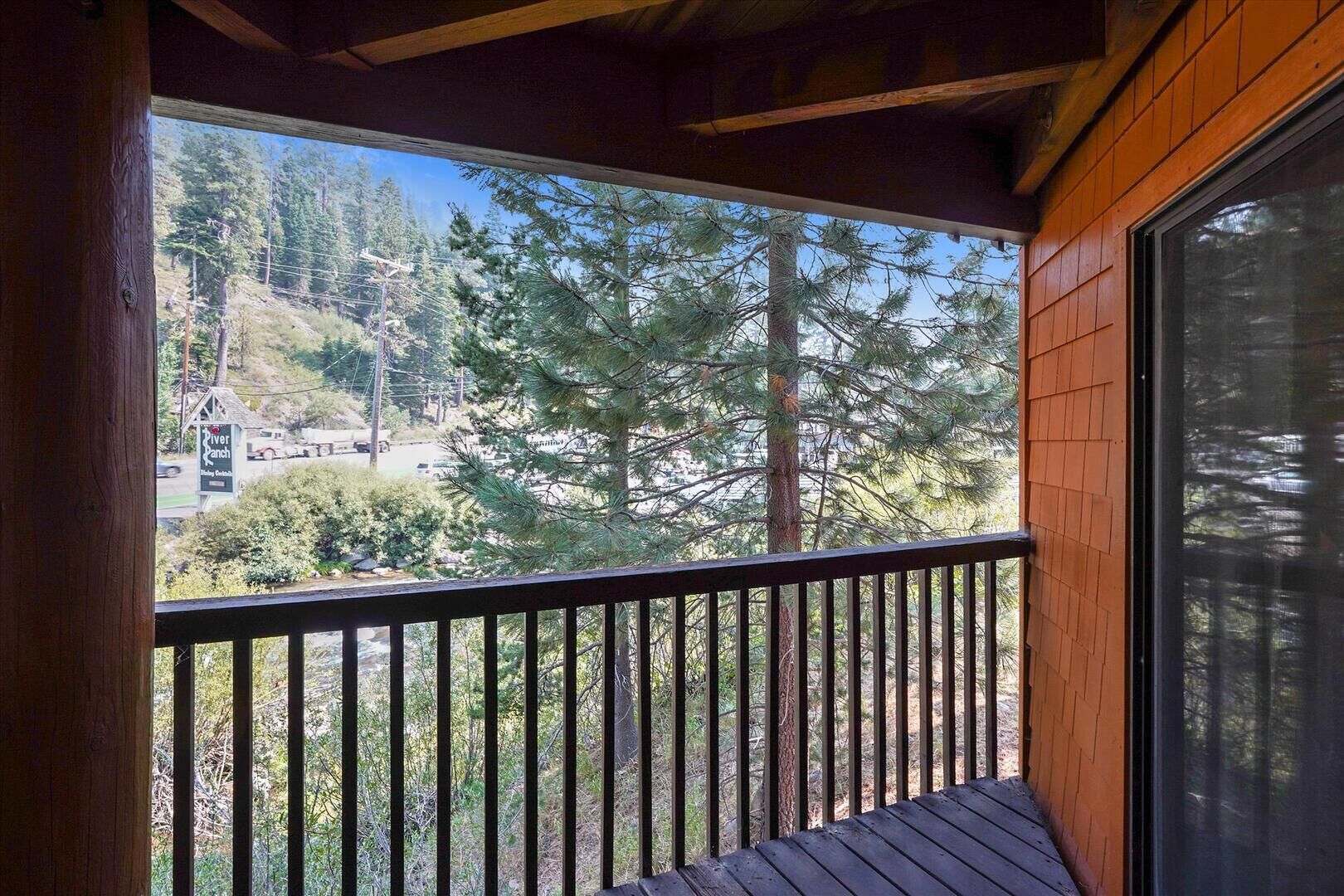 Un balcone in legno con vista su una zona boschiva e un cartello che riporta 'River Ranch'.