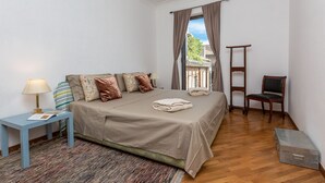 A bedroom with a bed, a nightstand, a chair, a suitcase, and a window with curtains. - Amazing New Penthouse with Terrace Jewish Ghetto  (Roma)