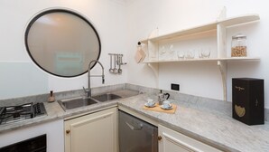 A kitchen with a round mirror, stainless steel sink, and a dish rack. There is a coffee maker, a jar of sugar, and a box on the counter. - Amazing New Penthouse with Terrace Jewish Ghetto  (Roma)