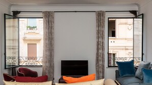 A living room with a sofa, a TV, and a fireplace. There are curtains on the windows, and a balcony is visible outside. - Amazing New Penthouse with Terrace Jewish Ghetto  (Roma)