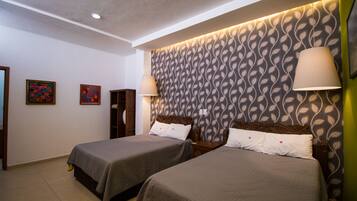 A hotel room with two beds, a patterned wallpaper, and a ceiling light.