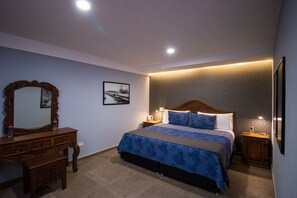 A bedroom with a bed, wooden dresser, nightstands, and a mirror. - Hotel Santa Rosa (San Pedro Cholula)