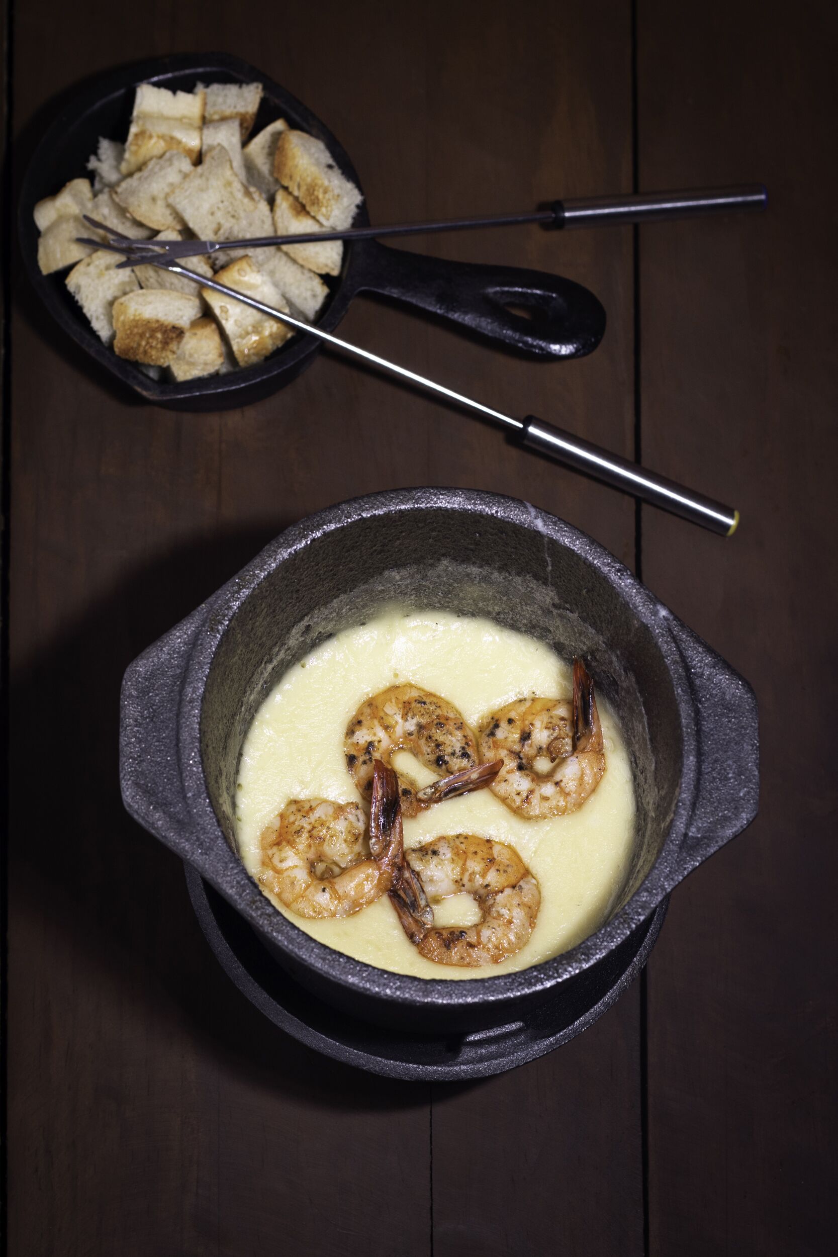 Una sartén con camarones y un bol de palitos de pan.