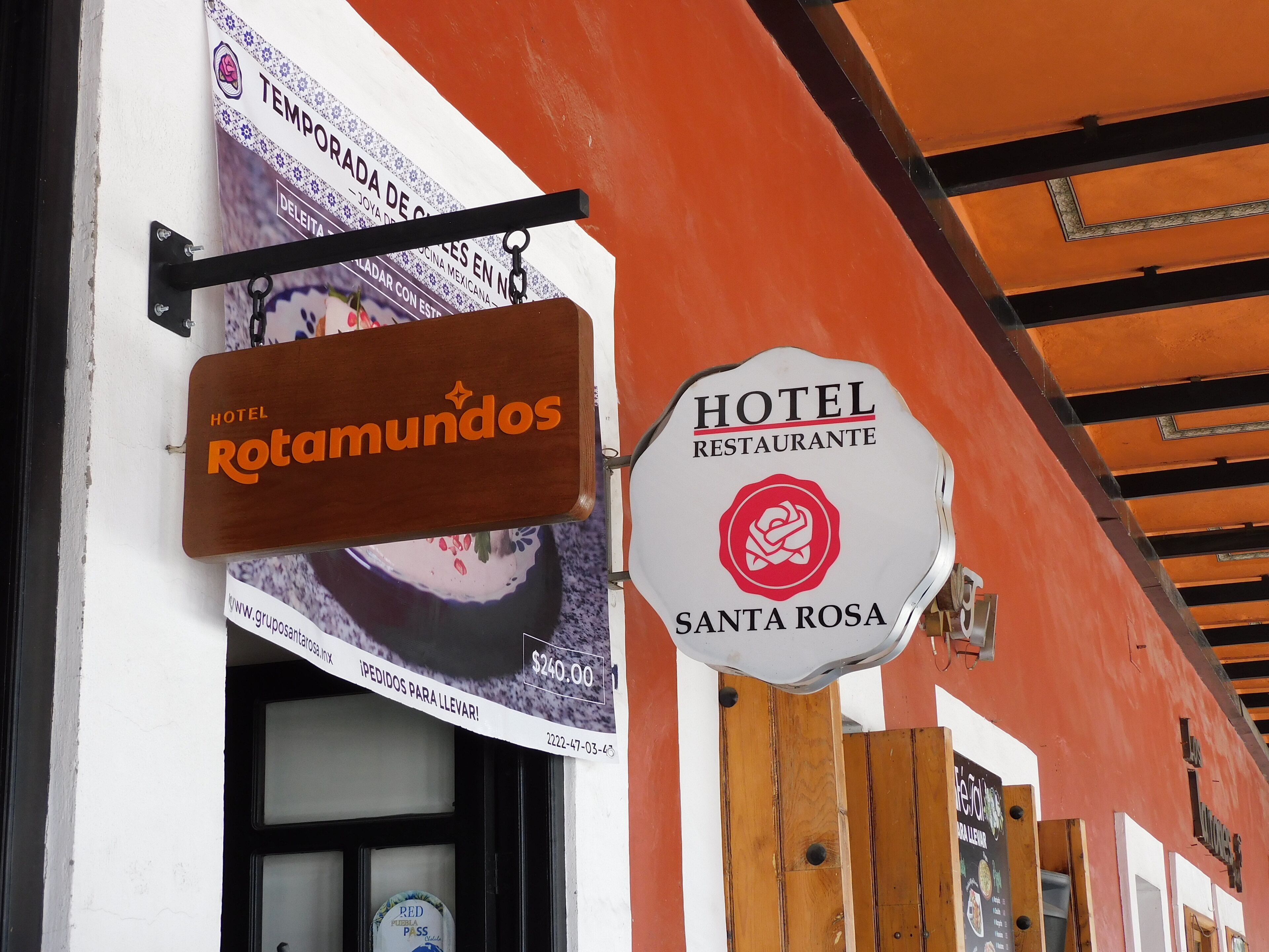 A hotel sign with "HOTEL RESTAURANTE SANTA ROSA" and a wooden sign for "HOTEL Rotamundos".