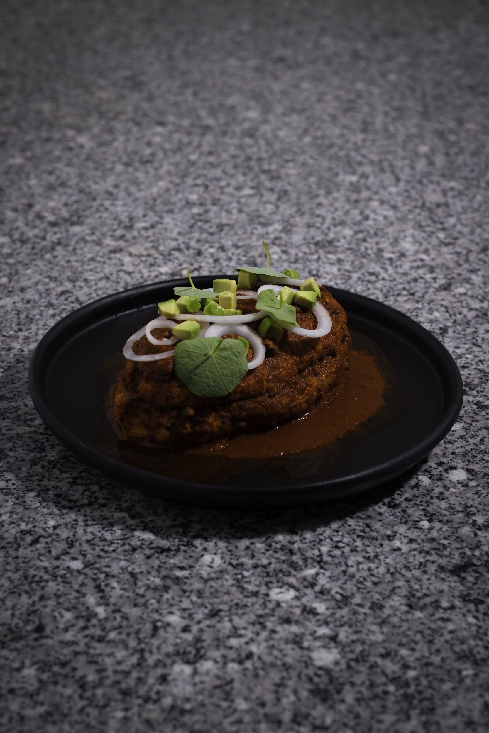 Un postre sobre un plato negro con superficie texturizada.