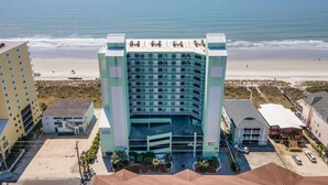 Un hôtel à plusieurs étages doté d’une cour intérieure, situé près d’une plage et offrant une vue sur l’océan.