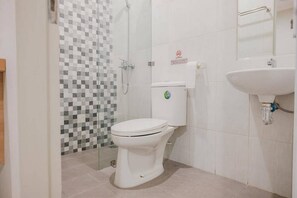 A bathroom with a toilet, a shower, and a sink.