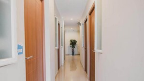 A hallway with wooden doors, a potted plant, and a sign with the number 103. - Reddoorz Plus Near Soekarno Hatta Airport Taman Mahkota (Tangerang)