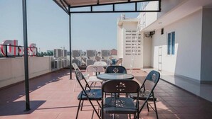 A rooftop terrace with a covered seating area, air conditioning units, and a view of the cityscape. - Reddoorz Plus Near Soekarno Hatta Airport Taman Mahkota (Tangerang)