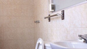 Un baño con inodoro, lavamanos y un cubo de basura azul.