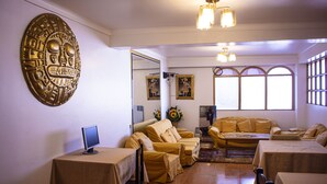 Una sala de estar con un gran adorno en la pared, un juego de sofá, una mesa de centro y un televisor sobre una mesa.