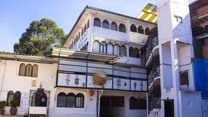 Un edificio con fachada blanca, varias ventanas y una escalera que lleva a un nivel superior.
