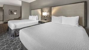 A hotel room with two beds, a nightstand, a chair, and a wall-mounted light fixture. - Best Western Plus Lawrenceburg (Lawrenceburg)