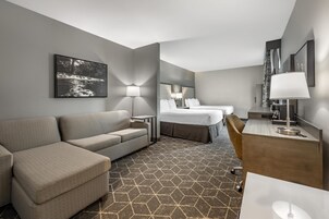 Una habitación de hotel con sofá, cama, escritorio y lámpara.