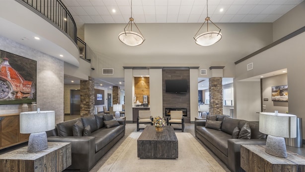A spacious living area with two sofas, a coffee table, and a TV mounted on the wall. - Best Western Plus Lawrenceburg (Lawrenceburg)