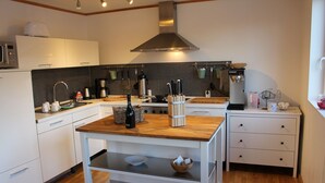 A modern kitchen with white cabinetry, a wooden countertop, and a stainless steel range hood.