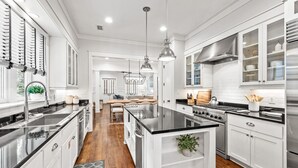 A modern kitchen with white cabinetry, stainless steel appliances, and pendant lighting. - WaterSound Retreat w/ Pool and Golf Cart (Panama City Beach)