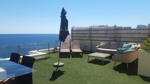 Une terrasse sur le toit, dotée d’un revêtement d’herbe artificielle, de mobilier d’extérieur et offrant une vue sur la mer.