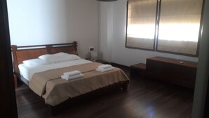 Une chambre à coucher avec un lit en bois, une table de chevet, une commode, un banc et une fenêtre avec des rideaux.