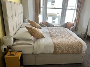 A neatly made bed with a headboard, multiple pillows, and a bedside lamp. - Harbour Lodge B&B (Paignton)