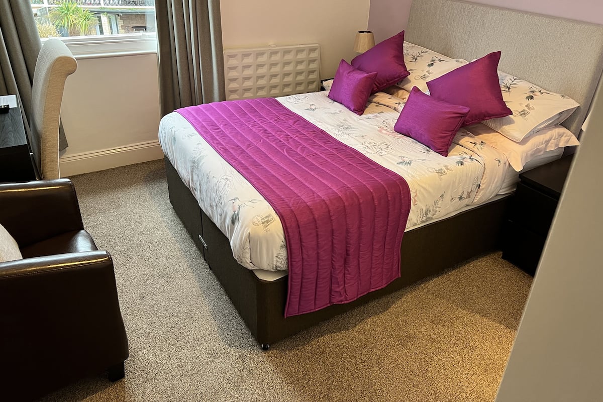 A bedroom with a bed, a chair, and a window.