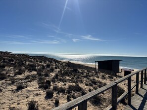 Ein Strand mit einer Holzpromenade, die zu einer kleinen Holzhütte führt.