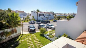 Un quartier résidentiel avec des maisons blanches, un parking et un ciel bleu dégagé.