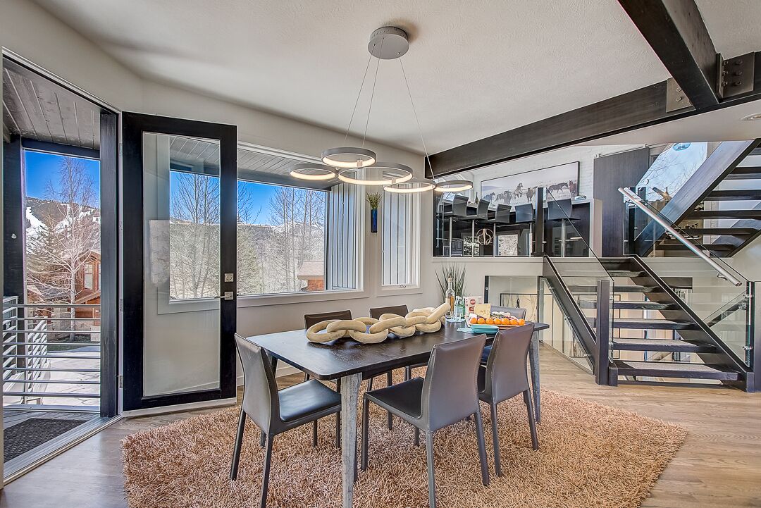 A modern dining area with a large table, chairs, and a unique light fixture.