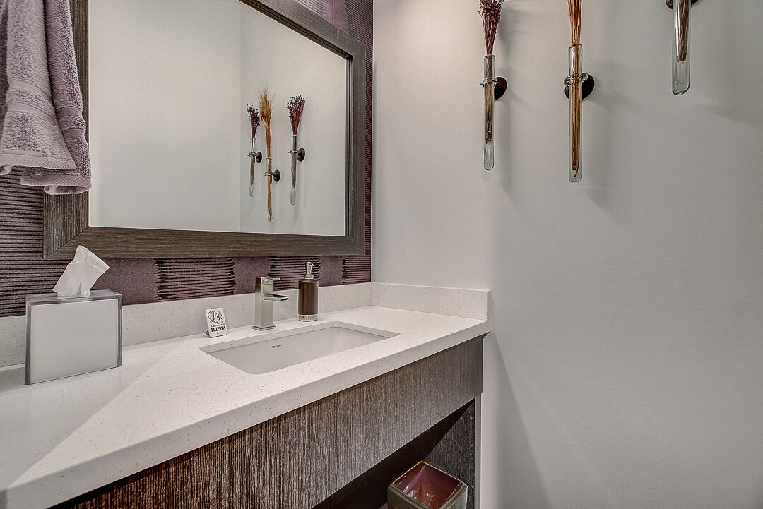 A modern bathroom with a large mirror, a sink, and a towel rack.