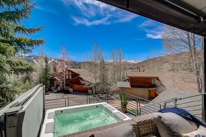 Un jacuzzi en una terraza con vistas a cabañas y montañas.