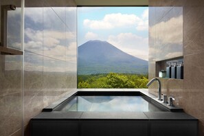 A bathroom with a large window offering a view of a mountain and greenery. - Higashiyama Niseko Village, a Ritz-Carlton Reserve (Niseko)