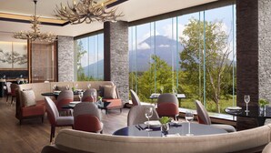 A modern dining area with a mountain view, featuring a mix of seating arrangements and a decorative chandelier. - Higashiyama Niseko Village, a Ritz-Carlton Reserve (Niseko)