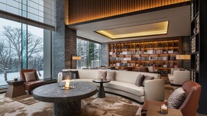 A modern interior with a curved sofa, a round table with a candle, and a bookshelf filled with books. - Higashiyama Niseko Village, a Ritz-Carlton Reserve (Niseko)