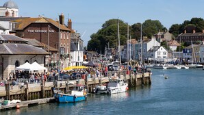 A bustling harbor with docked boats and a prominent building labeled "The George Inn". - The Royal Hotel (Weymouth)