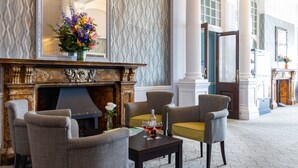 A lobby with a fireplace, seating area, and a mirror. - The Royal Hotel (Weymouth)