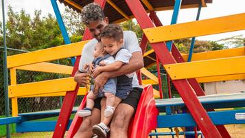 Kids can play on the playground structure with a slide and a roof overhead.
