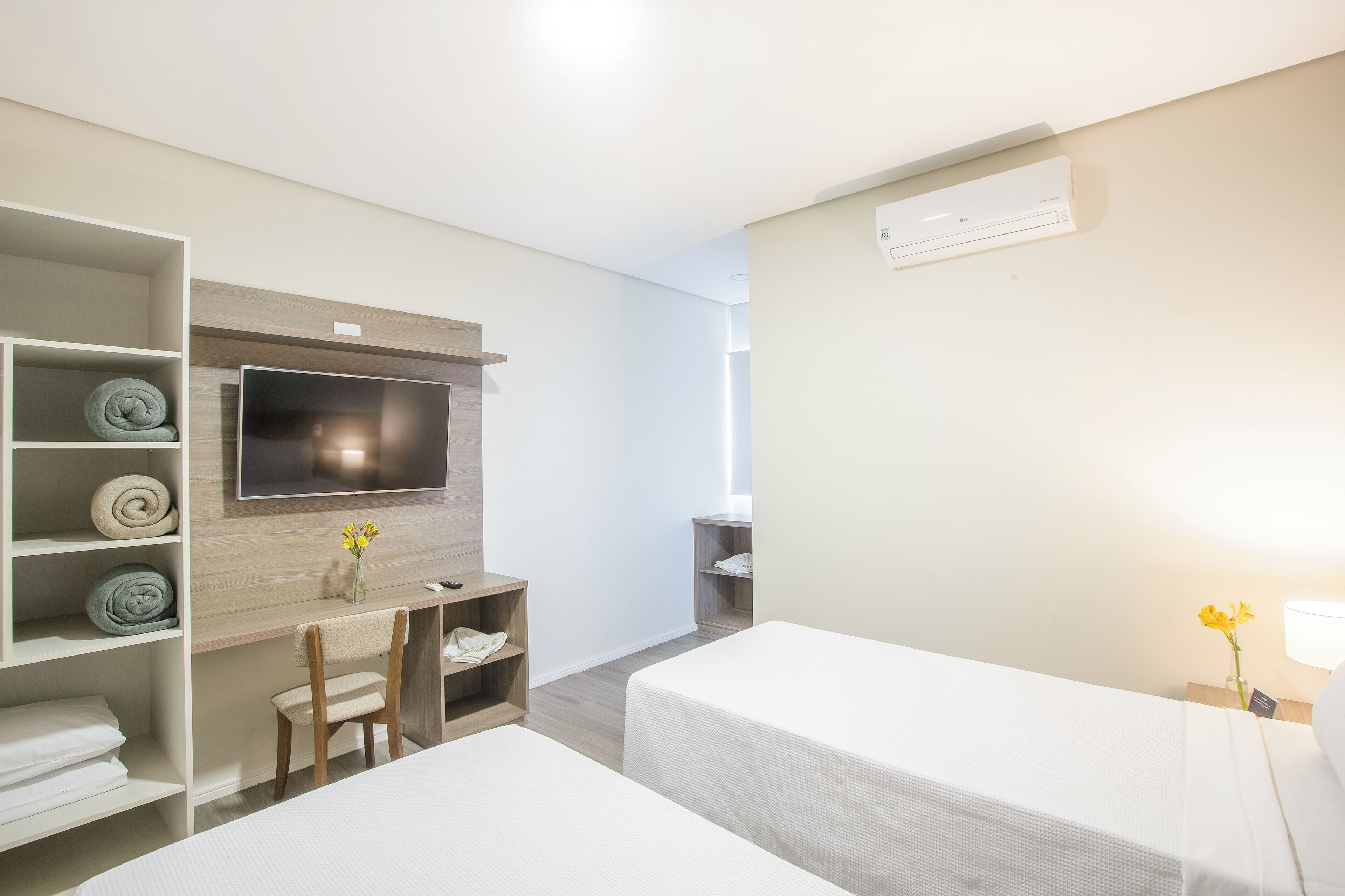 A hotel room with two beds, a TV, a desk, and a chair.