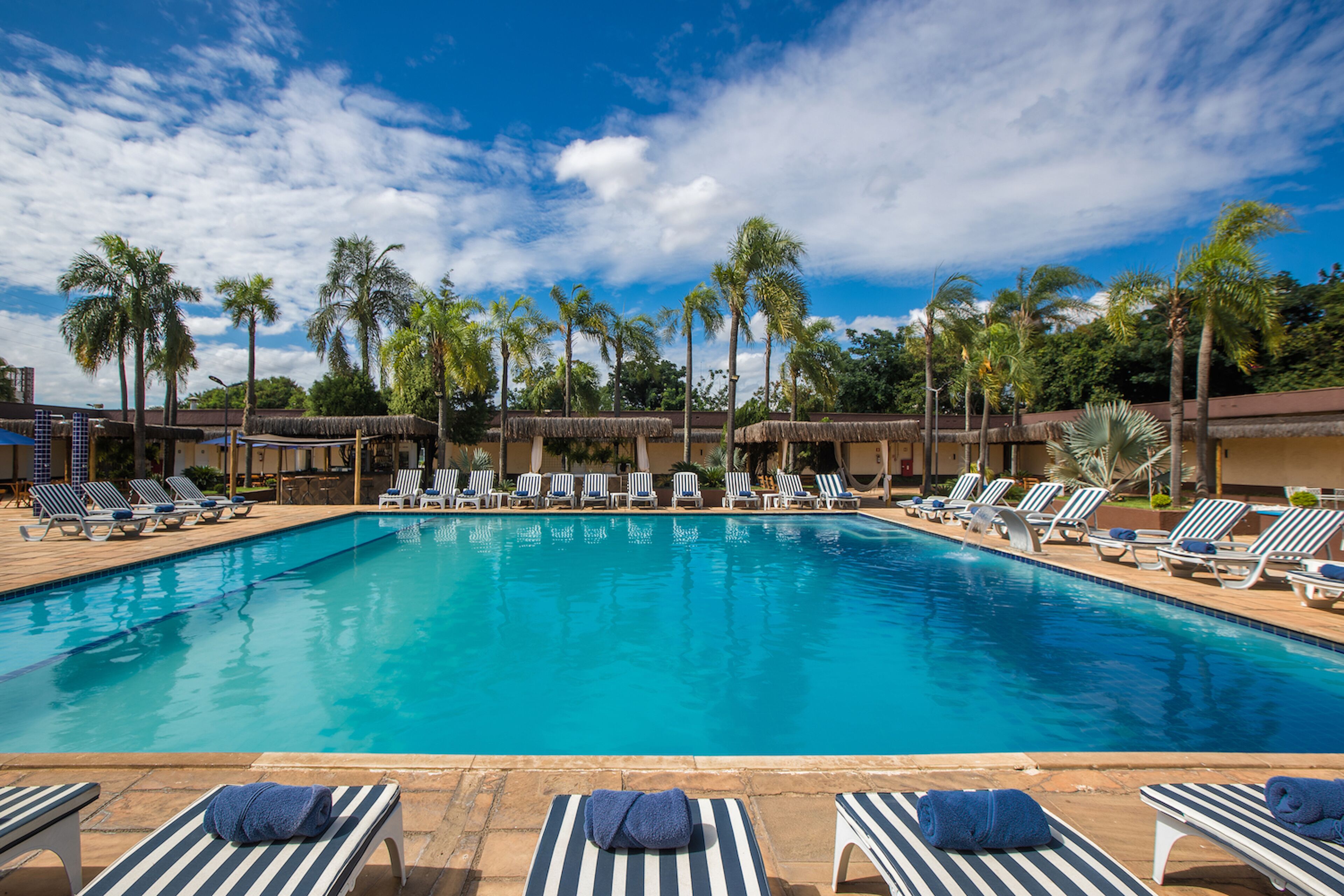 Piscina com espreguiçadeiras e palmeiras.