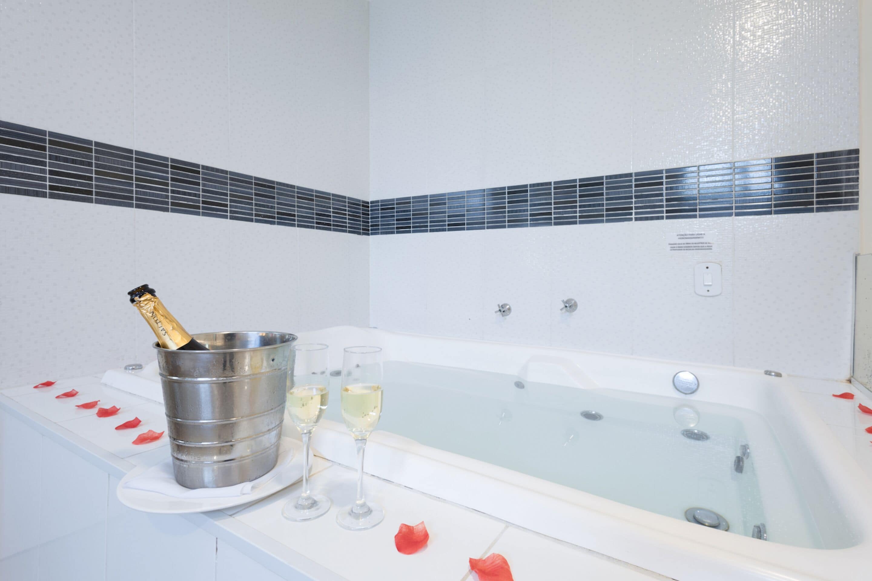 Une salle de bain avec une baignoire, une bouteille de champagne dans un seau, et deux coupes de champagne.