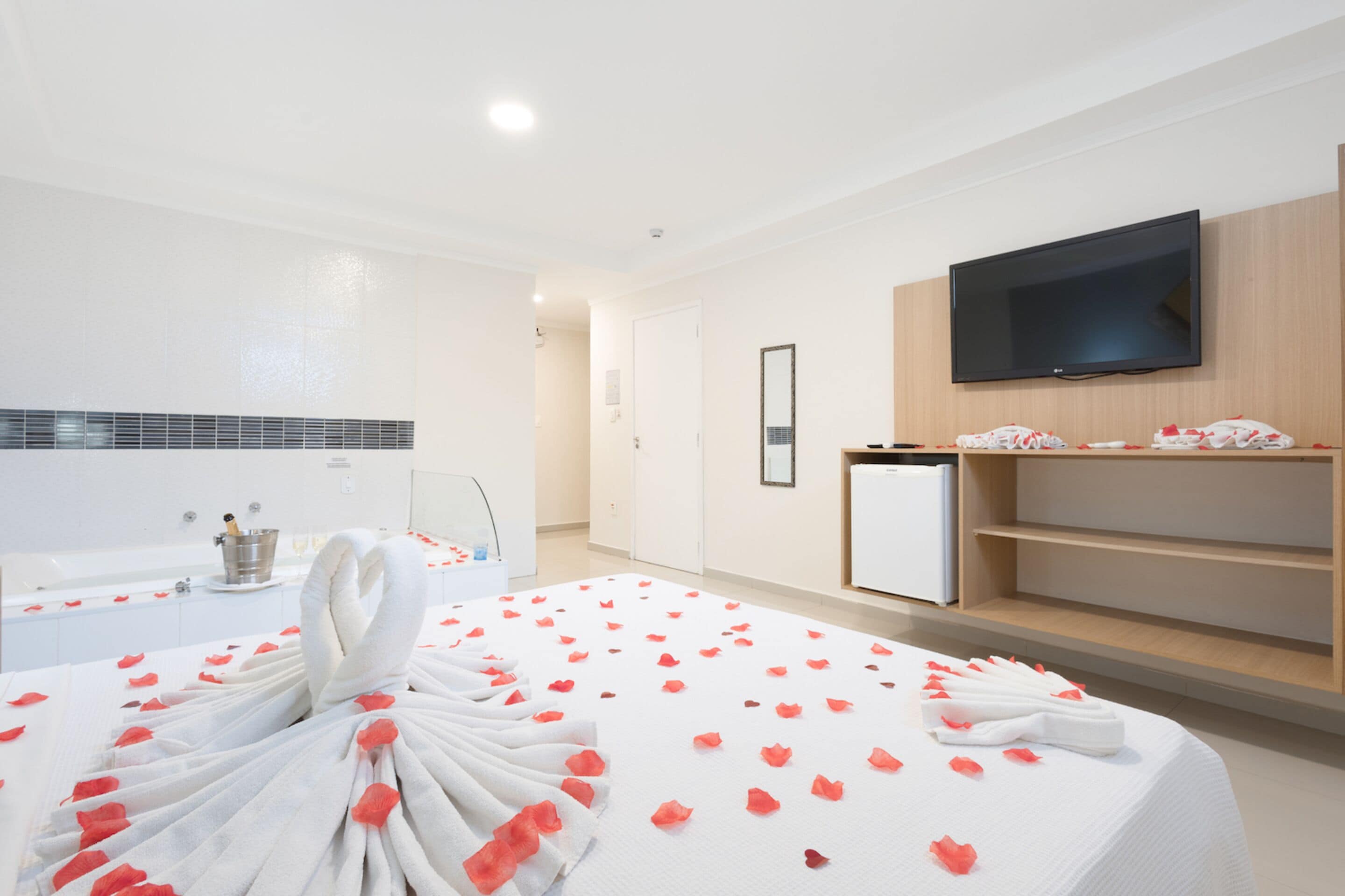 Habitación de hotel con cama, televisión, minibar y zona de ducha.